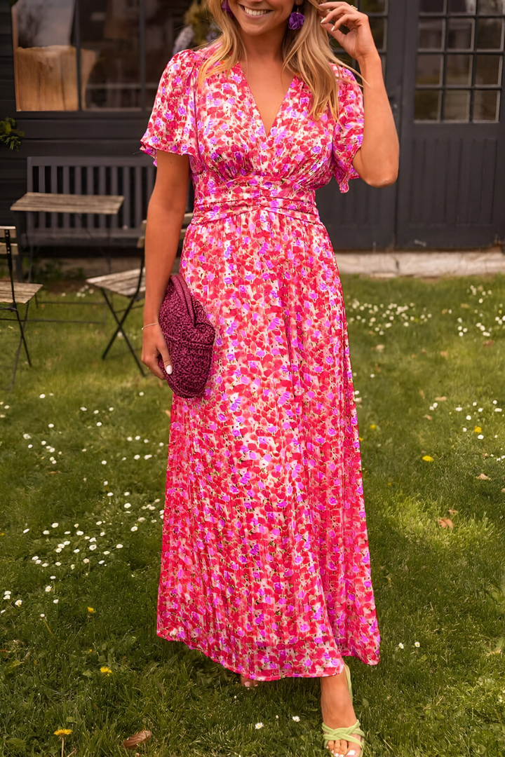 Robe maxi rose à imprimé floral, avec décolleté en V et taille ajustée qui met en valeur la silhouette. Sa matière fluide et légère offre un confort optimal, parfaite pour un look féminin et raffiné lors des journées d’été ou des occasions spéciales.