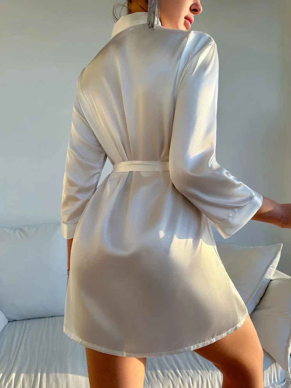 Kimono en satin pour femme Roseline, de couleur blanc ivoire, vu de dos, avec ceinture à nouer et manches trois-quarts, porté dans un intérieur lumineux pour une allure tendance et agréable.