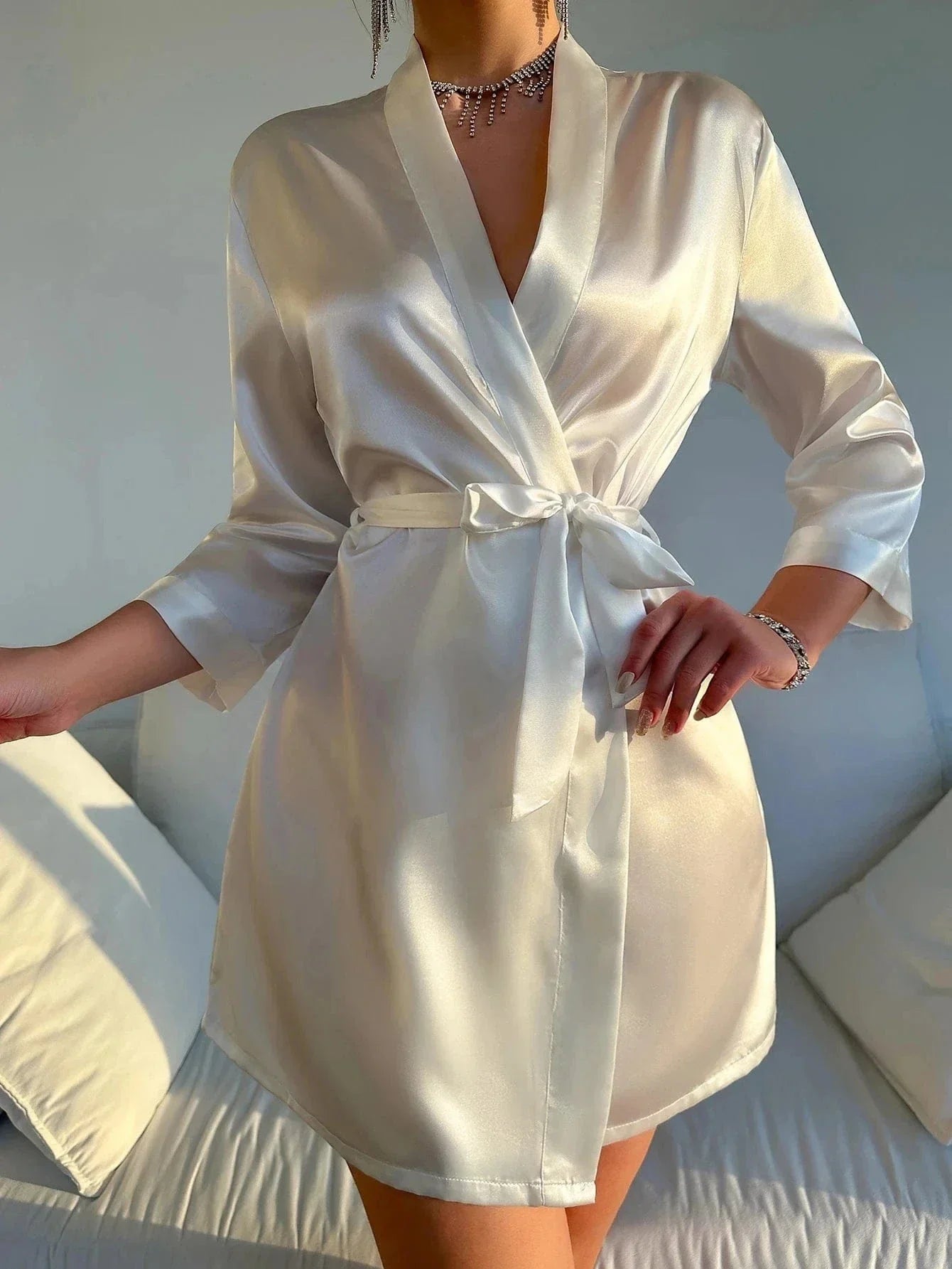 Kimono satin femme Roseline blanc, vue de face, avec col croisé, manches trois-quarts et ceinture nouée à la taille, porté dans un intérieur lumineux au style épuré.
