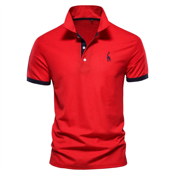 Polo pour homme de couleur rouge avec des accents bleu marine sur le col et les manches. Il présente un logo de girafe bleu sur la poitrine. Ce polo combine à la fois confort et élégance, idéal pour une tenue décontractée et stylée pendant l&