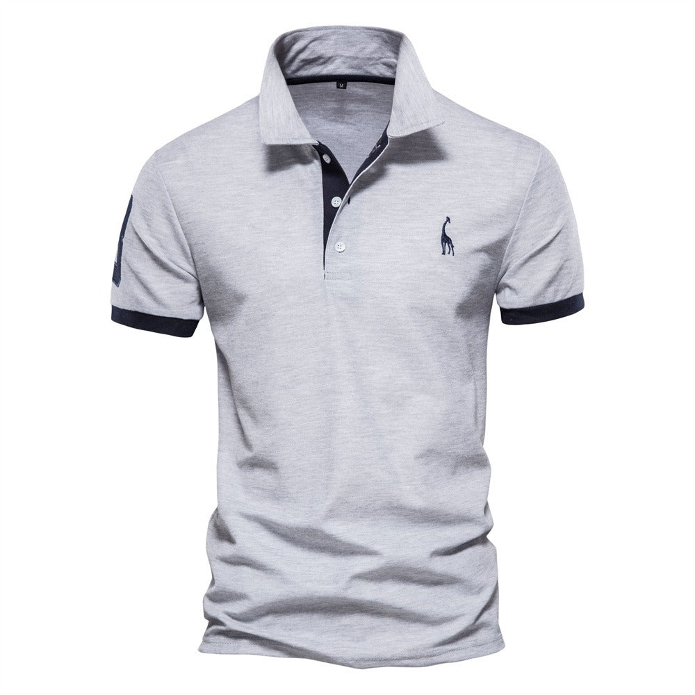 Polo pour homme de couleur grise avec des accents bleu marine sur le col et les manches. Il présente un logo de girafe bleu sur la poitrine. Ce polo allie confort et style, idéal pour une tenue décontractée et chic durant l&