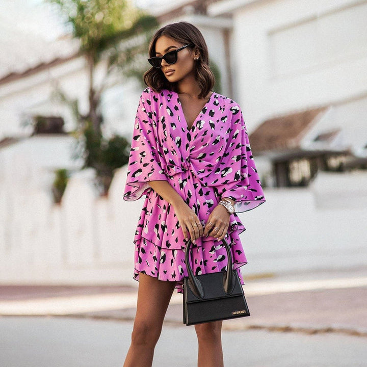 Femme portant une robe mini fleurie rose avec un motif abstrait, parfaite pour l&