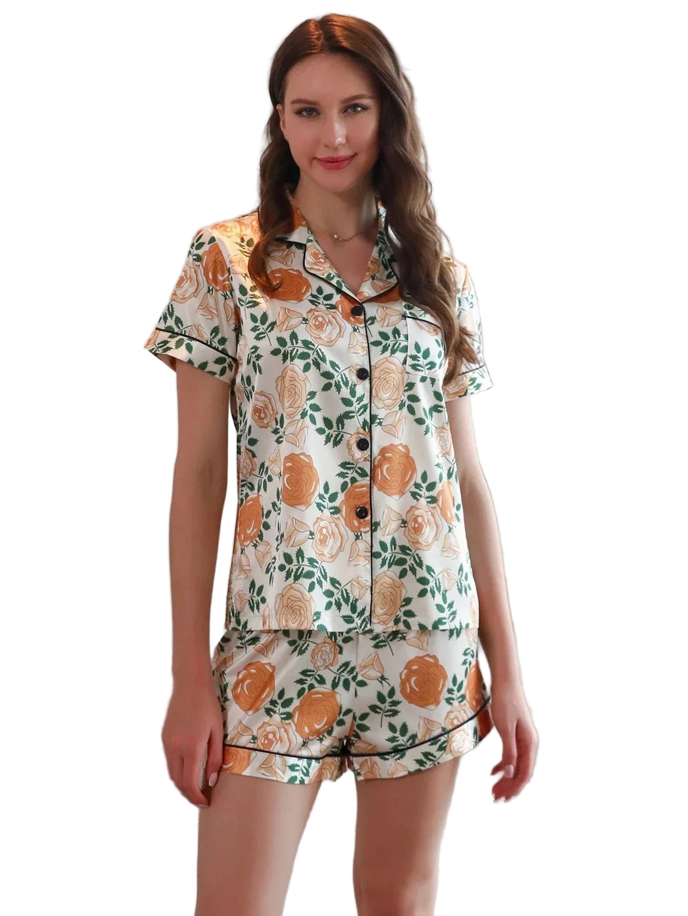 Femme portant le pyjama satin, un ensemble léger, doux et élégant composé d’une chemise à manches courtes et d’un short assorti en satin blanc imprimé de fleurs orange et de feuillage vert, photographiée dans un intérieur lumineux.