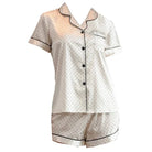 ensemble en satin blanc à petits pois noirs composé d’une chemise à manches courtes boutonnée et d’un short assorti, offrant un style élégant et agréable pour la nuit.