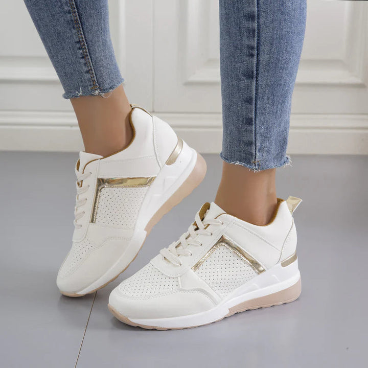 Baskets blanches en cuir avec accents métalliques dorés et semelle compensée beige. Parfaites pour allier confort et élégance au quotidien, idéales pour une allure moderne et décontractée.