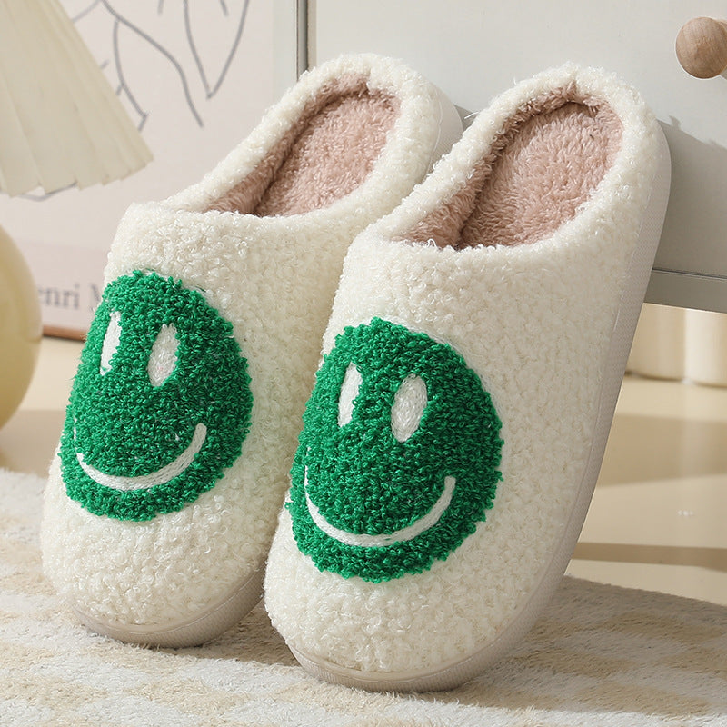 Chaussons unisexe Sasha blancs en matière pelucheuse avec motif smiley vert, intérieur chaud et doux, semelle confortable, idéals pour un look cosy à la maison.