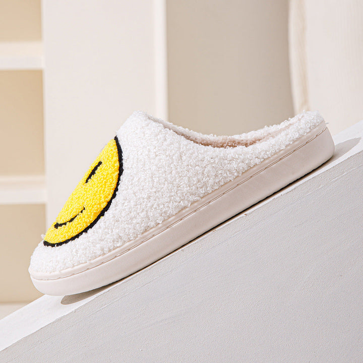 Vue de profil des chaussons unisexe Sasha blancs en matière pelucheuse avec motif smiley jaune, intérieur chaud et doux, semelle épaisse confortable pour la maison.