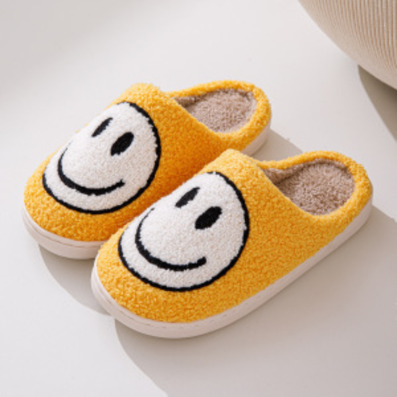 Chaussons unisexe Sasha jaunes en matière pelucheuse avec grand motif smiley blanc, intérieur chaud et moelleux, semelle confortable, parfaits pour un style cosy à la maison.