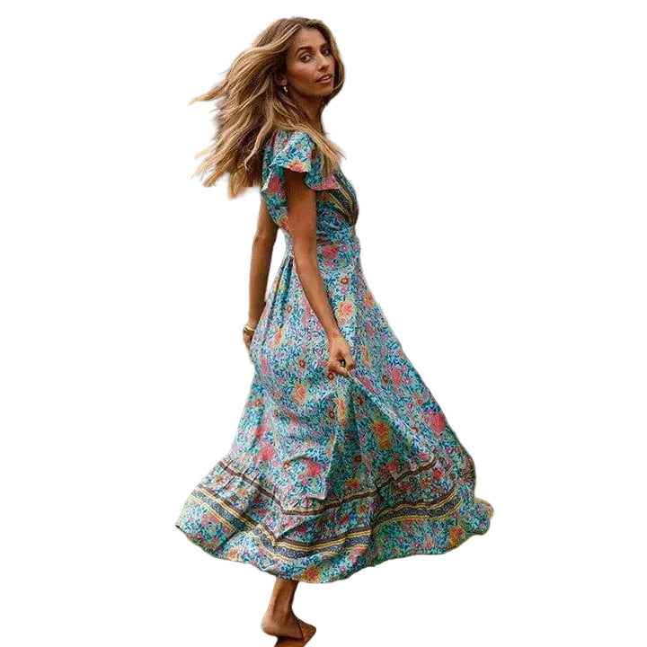 Robe maxi femme Sydney fluide à imprimé coloré avec manches courtes et coupe évasée, portée en mouvement dans un jardin pour un style élégant, léger et estival.