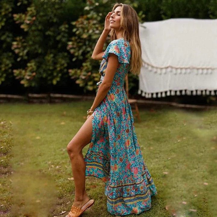 Robe maxi femme Sydney fluide à imprimé coloré avec manches courtes et fente sur la jambe, portée dans un jardin pour un style élégant, léger et estival.