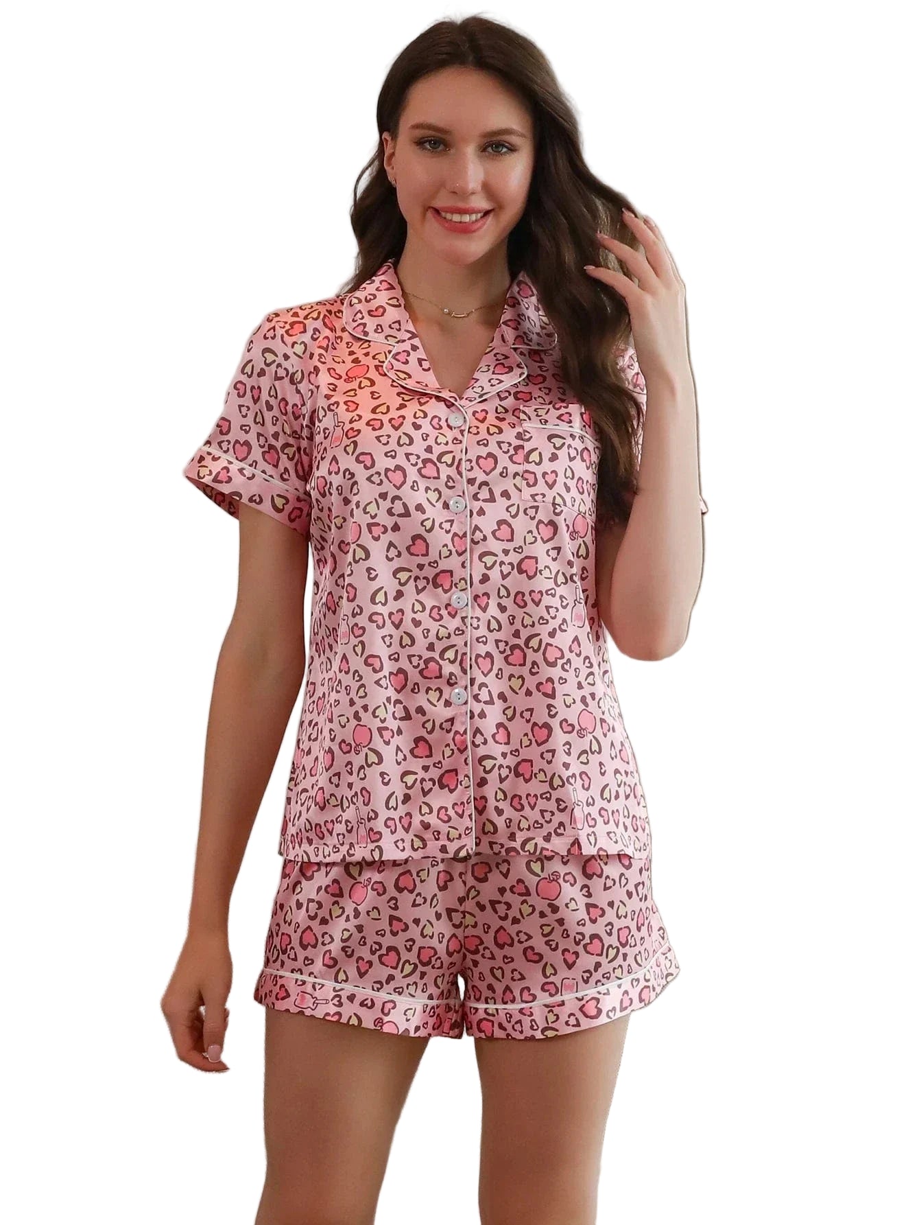 Femme portant le pyjama satin femme, un ensemble léger et élégant en satin rose, composé d’une chemise à manches courtes et d’un short assorti avec imprimé cœurs et léopard.