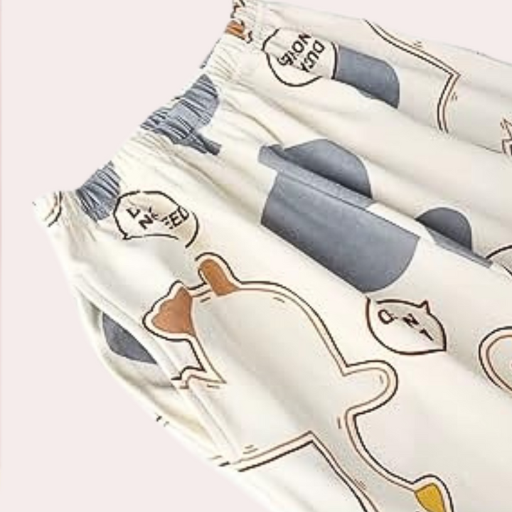 Gros plan du pantalon du pyjama femme Thérèse, taille élastique confortable avec imprimé canards et pois bleus sur tissu crème doux.