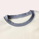 Gros plan sur l’encolure du haut du pyjama femme Thérèse, col rond bleu contrastant sur tissu crème doux, finition confortable et soignée.