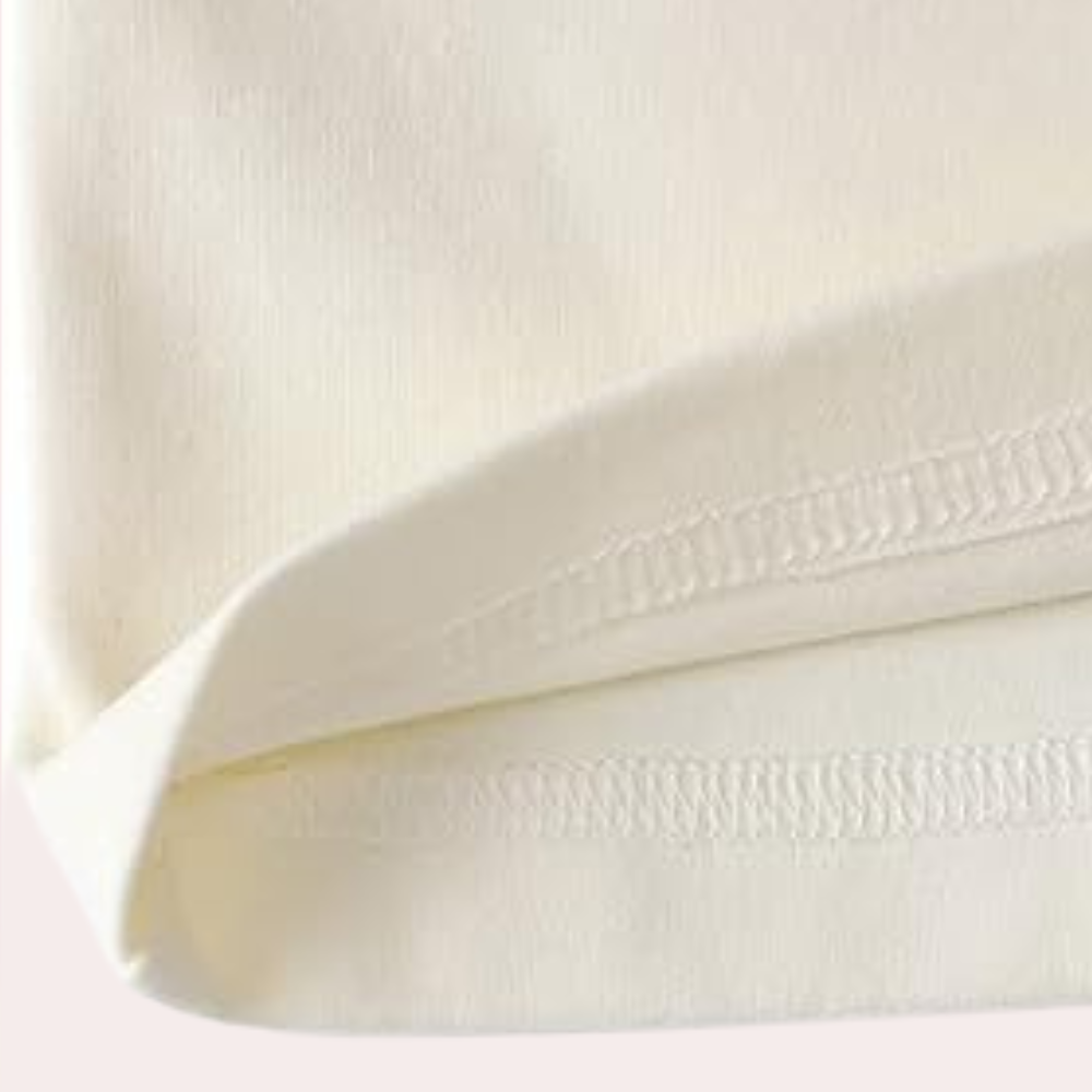 Gros plan sur la finition de l’ourlet du haut du pyjama femme Thérèse, couture nette et tissu crème doux pour un confort optimal.