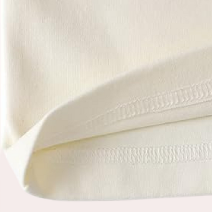 Gros plan sur la finition de l’ourlet du haut du pyjama femme Thérèse, couture nette et tissu crème doux pour un confort optimal.