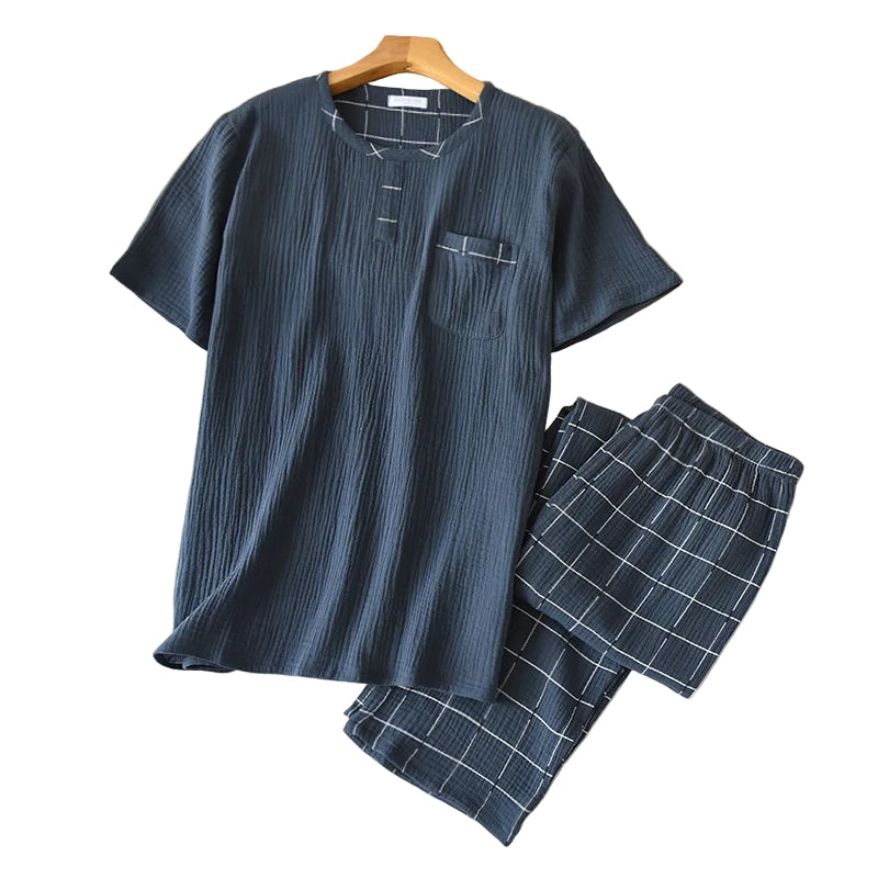 Pyjama homme Yanis en tissu léger texturé bleu foncé, composé d’un haut à manches courtes avec col rond et poche poitrine, et d’un pantalon assorti à carreaux blancs. Ensemble tendance et agréable, parfait pour les nuits d’été ou les moments de détente à la maison.