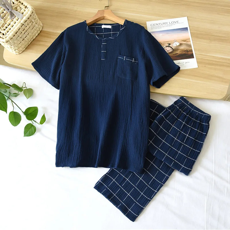 Pyjama homme Yanis en coton gaufré bleu marine, composé d’un haut à manches courtes avec col fendu et poche poitrine à motif carreaux, accompagné d’un pantalon court assorti à carreaux blancs. Ensemble tendance, léger et agréable, idéal pour les nuits d’été ou la détente à la maison.