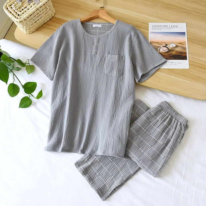 Pyjama homme Yanis en coton gaufré gris clair, composé d’un haut à manches courtes avec col fendu et poche poitrine, assorti à un pantalon court à carreaux blancs. Ensemble tendance, léger et agréable, parfait pour les nuits estivales et la détente à la maison.