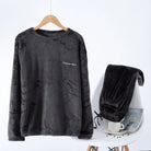 Pyjama femme Valérie en polaire gris anthracite, composé d’un haut à manches longues suspendu sur cintre et d’un pantalon assorti déposé sur une chaise blanche. Ensemble confortable, chaud et douillet, parfait pour l’hiver et les moments de détente à la maison.