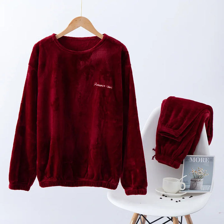 Pyjama femme Valérie en polaire rouge bordeaux, avec un haut à manches longues suspendu sur cintre et un pantalon assorti soigneusement posé sur une chaise blanche. Ensemble chaud et douillet, parfait pour affronter l’hiver avec confort et élégance.