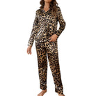 Femme portant un ensemble pyjama en satin imprimé léopard, élégant et confortable. Le haut à manches longues est boutonné et le pantalon à coupe fluide complète l'ensemble. Elle affiche une pose décontractée tout en mettant en valeur le style chic et raffiné du pyjama.