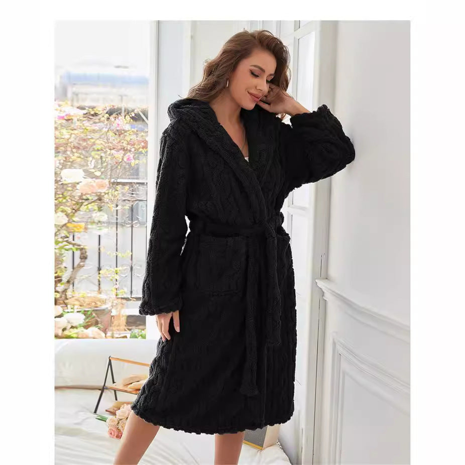 Peignoir femme Vanessa noir, doux et confortable, texture torsadée avec capuche et ceinture à nouer, porté debout près d’une fenêtre.