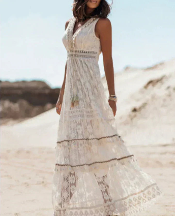 Femme portant une robe longue en dentelle blanche, avec des détails bohèmes et un design fluide, idéale pour une occasion estivale, alliant confort et élégance au quotidien.
