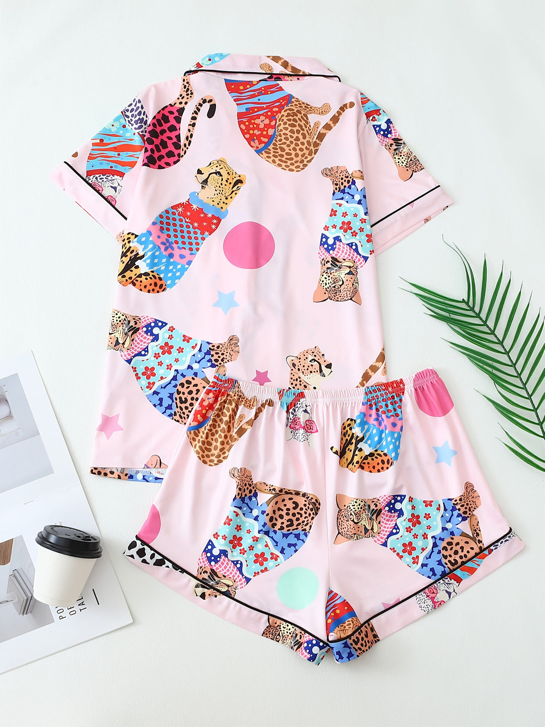 Pyjama femme deux pièces vu de dos, composé d’un haut à manches courtes et d’un short, en satin rose imprimé de félins colorés et de motifs graphiques. Style original et décontracté, parfait pour les nuits d’été ou les matinées relax à la maison.