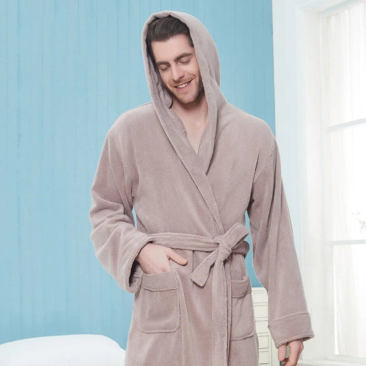 un peignoir long beige à capuche en tissu doux avec ceinture et poches avant, offrant chaleur, confort et style pour la maison.
