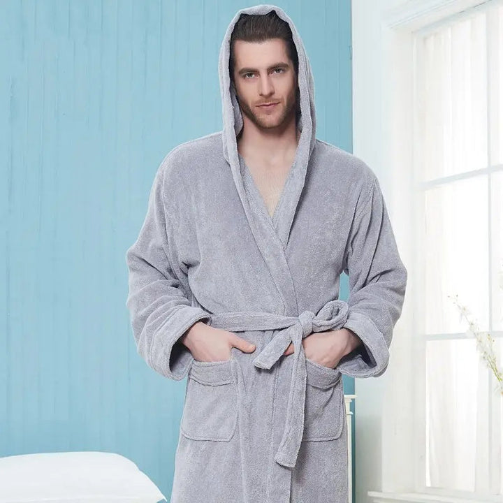 un peignoir gris à capuche en tissu doux avec ceinture et poches avant, offrant chaleur, confort et style pour se détendre à la maison.