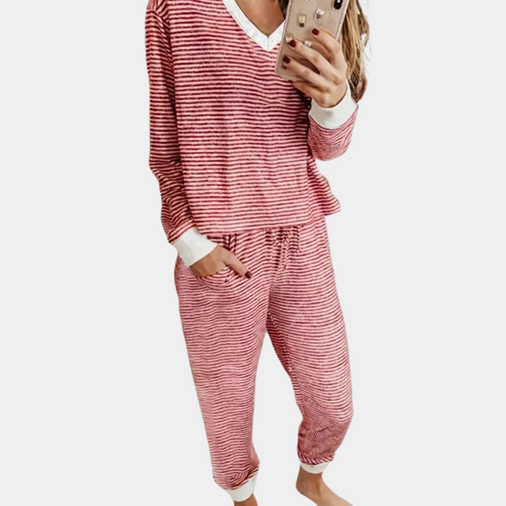 Femme portant le pyjama Winifred, un ensemble doux et élégant composé d’un haut à manches longues et d’un pantalon assorti à fines rayures rouges et blanches, idéal pour un look confortable et stylé à la maison.