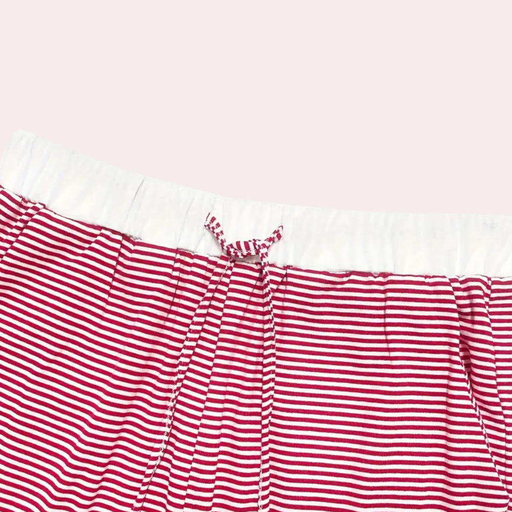 Gros plan sur le pantalon du pyjama Winifred, à fines rayures rouges et blanches, doté d’une taille élastique confortable avec cordon de serrage assorti, offrant douceur et élégance pour la détente à la maison.