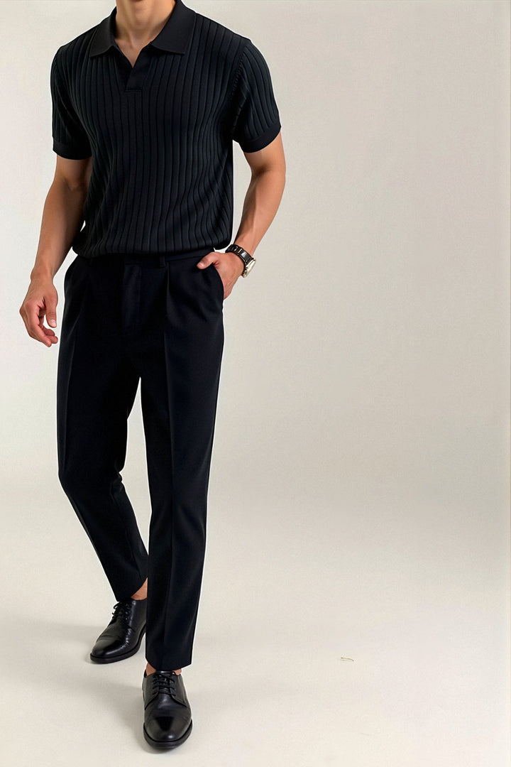 Polo côtelé noir porté avec un pantalon noir et des chaussures élégantes, offrant un look moderne, raffiné et décontracté.