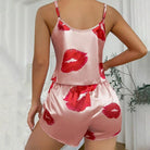 Vue arrière d’une femme portant un ensemble shorty en satin rose clair orné de baisers rouges. Haut à fines bretelles et dos droit, avec short assorti à taille élastique. Ensemble tendance, féminin et agréable à porter, parfait pour les soirées cocooning ou les nuits estivales.