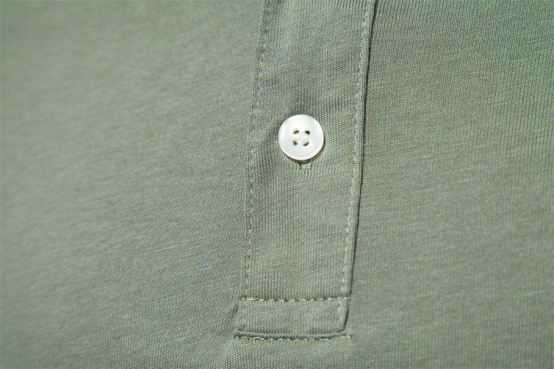 Zoom sur le détail du col du polo vert kaki, mettant en valeur le bouton élégant et la finition soignée. Ce polo combine à la perfection un design simple avec des touches raffinées pour un look chic et confortable.