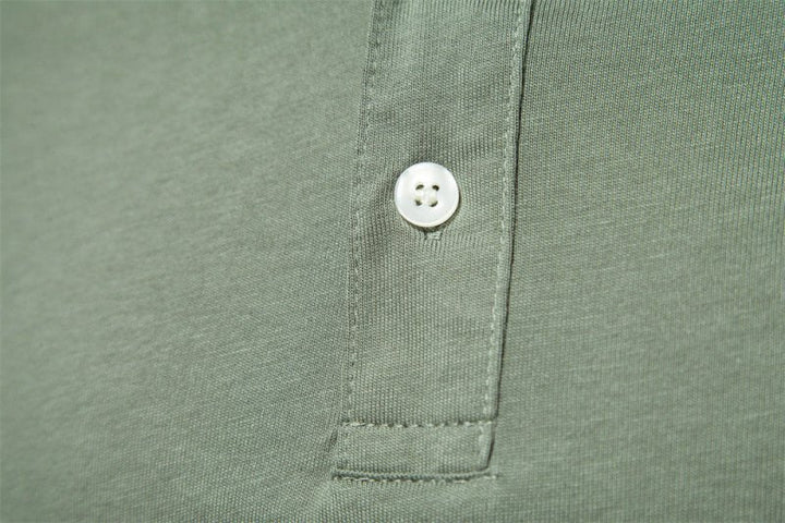Zoom sur le détail du col du polo vert kaki, mettant en valeur le bouton élégant et la finition soignée. Ce polo combine à la perfection un design simple avec des touches raffinées pour un look chic et confortable.