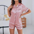 Femme portant le pyjama Élise en satin rose pâle à manches courtes, avec passepoil noir élégant et boutons blancs. Ensemble léger et raffiné, parfait pour des nuits confortables tout en élégance.