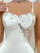 Gros plan sur le haut de la nuisette Éloïse en satin blanc, avec bonnets à armatures décorés de fleurs brodées et empiècement en dentelle transparente sur le côté. Lingerie raffinée et sensuelle, idéale pour un look élégant et séduisant.