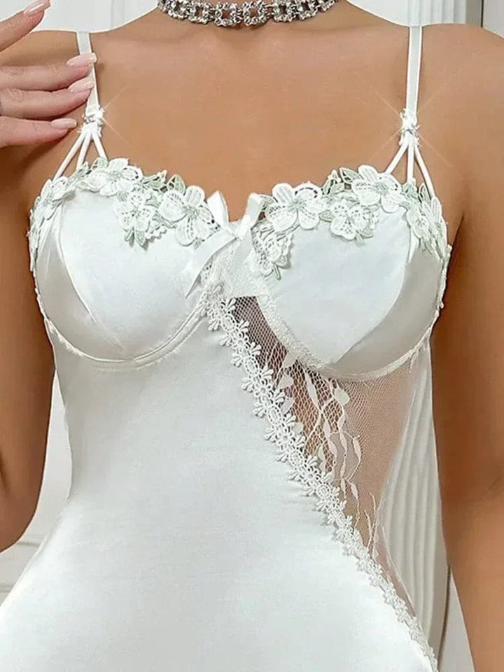 Gros plan sur le haut de la nuisette Éloïse en satin blanc, avec bonnets à armatures décorés de fleurs brodées et empiècement en dentelle transparente sur le côté. Lingerie raffinée et sensuelle, idéale pour un look élégant et séduisant.