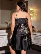 Vue de dos d’une femme portant une nuisette satinée noire à fines bretelles, ornée de motifs floraux dorés. Lingerie fluide et élégante, offrant un tombé doux et raffiné, parfaite pour une allure féminine et confortable à la maison.