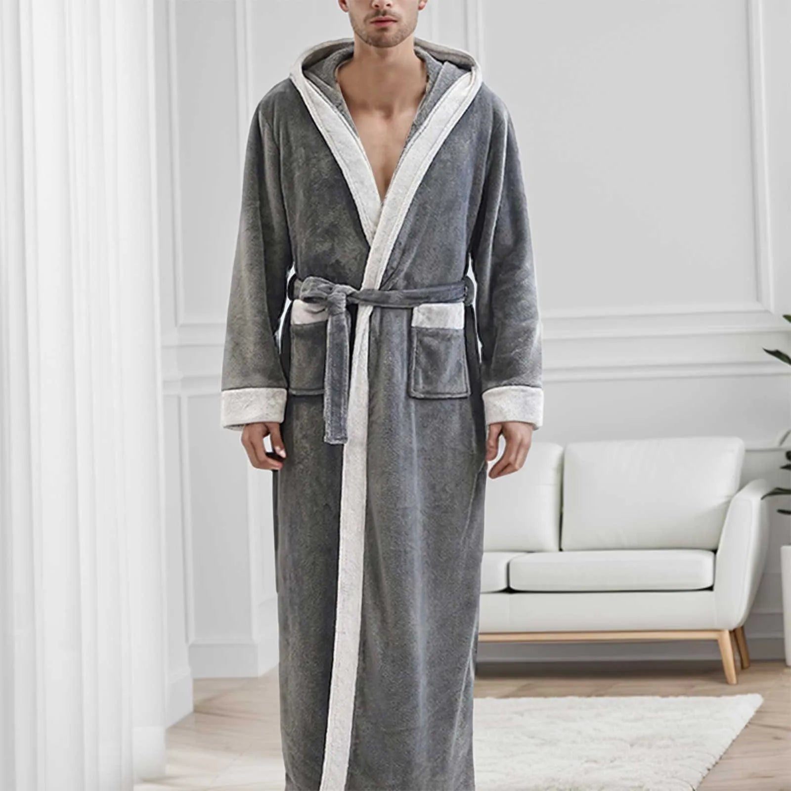 Homme portant le peignoir Étienne, modèle chaud et idéal pour l’hiver en tissu gris doux avec bordures crème et ceinture assortie, présenté dans un intérieur moderne et lumineux.